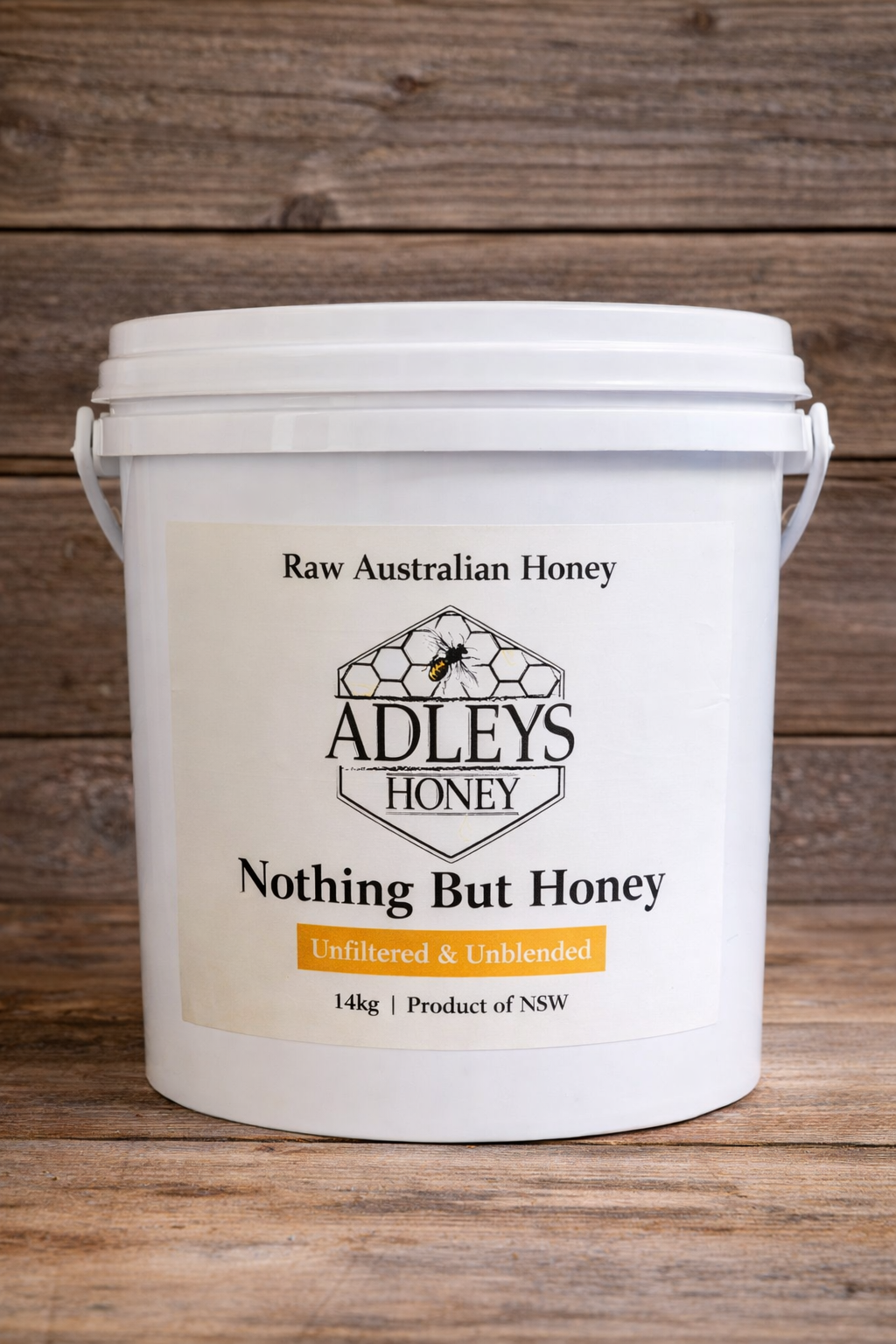 White bucket of Adley's Raw Australian Honey on a wooden background