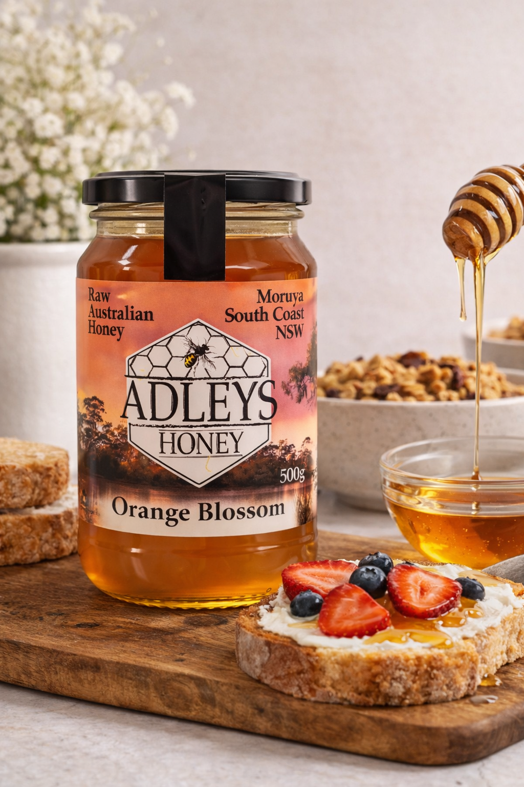 Adleys  Orange Blossom Honey 500g glass jar with black lid sert in breakfast setting.